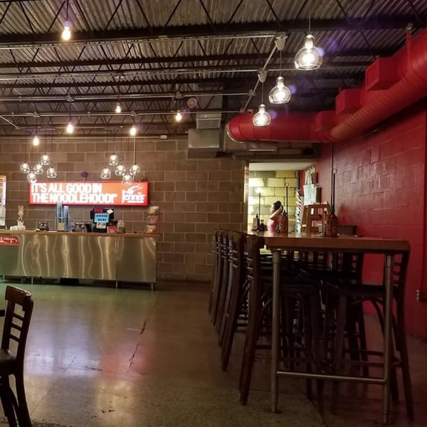 Interior of Jenni's Noodle House with a red wall, brick, and industrial lighting.