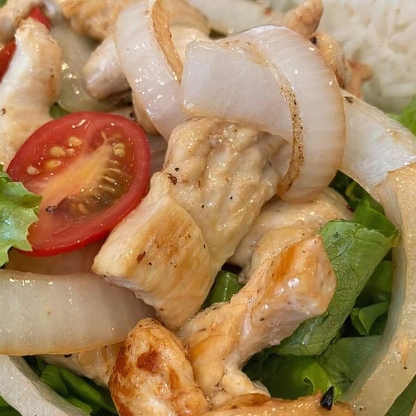 Close-up of a Vietnamese chicken salad with grilled chicken, onions, lettuce, and tomato.