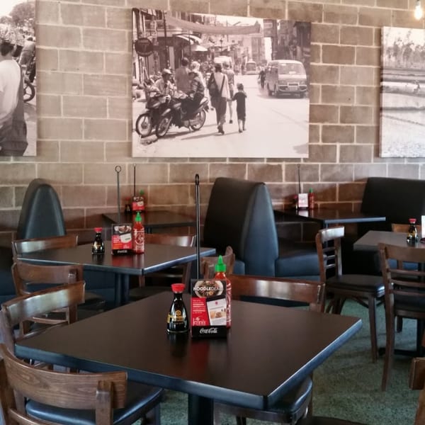 Interior of Jenni's Noodle House with tables, chairs, booths, and black and white street scene photos.