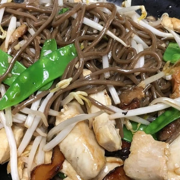 Close-up of Vietnamese stir-fried noodles with chicken, bean sprouts, snow peas, and mushrooms.